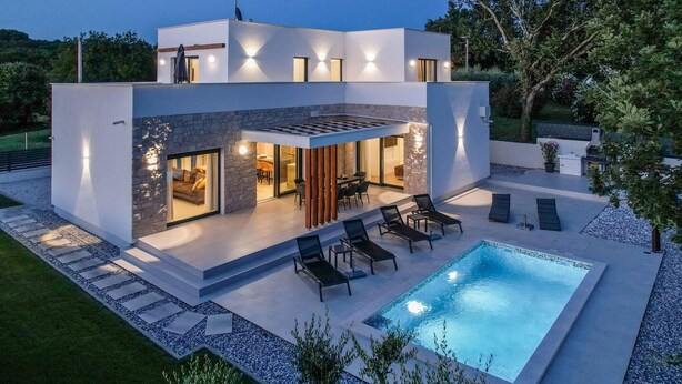 A modern two-story house with a swimming pool, outdoor seating, and a stone facade. - Luxurious home in Marasi (Marasi)