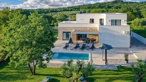 A modern house with a swimming pool, outdoor seating, and a lush garden. - Luxurious home in Marasi (Marasi)