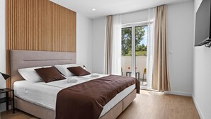 A modern bedroom with a large bed, a wooden headboard, a balcony with a view, and a flat-screen TV mounted on the wall. - Luxurious home in Marasi (Marasi)