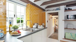 A kitchen with a brick backsplash, white cabinets, and a window.