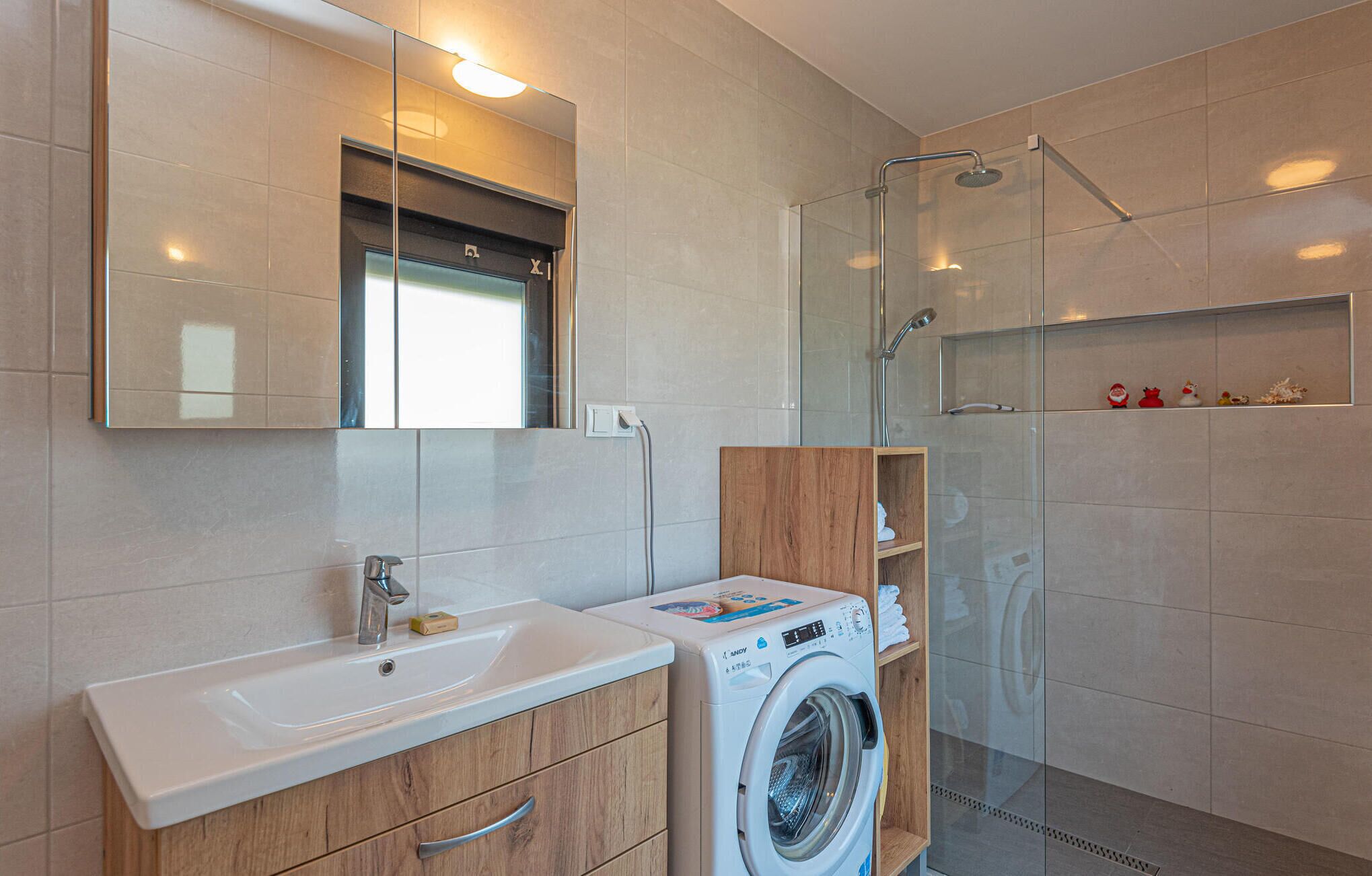 Ein modernes Badezimmer mit Waschbecken, Spiegel und einer Duschkabine aus Glas.