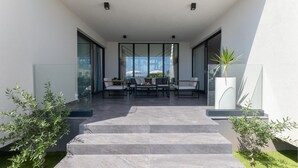 A modern outdoor patio with a dining area, steps leading to a glass door, and potted plants. - Cozy home in Kastel Stari with sauna (Kastel Stari)