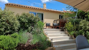 A patio area with outdoor furniture, a pergola, and a view of a building with a tiled roof.