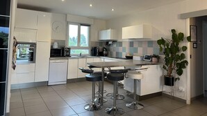 A modern kitchen with white cabinets, a large window, and a bar area with stools.