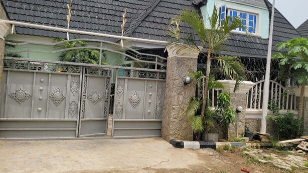 A gated residential property with a stone pillar, metal gate, and a paved driveway. - Dazzle Hotels and Apartments (Abuja)