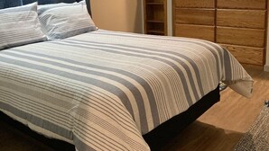 A bedroom with a bed, a wooden wardrobe, a framed picture on the wall, and a blue curtain. - Updated family home in quiet neighborhood.   (El Dorado)