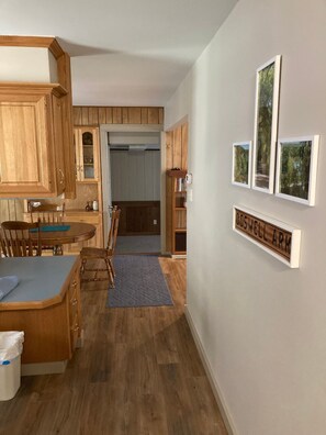 A compact kitchen with wooden cabinets, a dining area with a table and chairs, and a hallway leading to a door. - Updated family home in quiet neighborhood. (El Dorado)