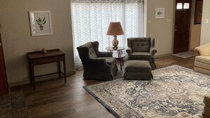 A living room with two armchairs, a small table, a lamp, a patterned rug, and a door in the background. - Updated family home in quiet neighborhood.   (El Dorado)