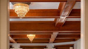 Una sala de estar con techo de madera, una araña, un sofá con cojines amarillos, una mesa de comedor con sillas amarillas y un televisor sobre un mueble.