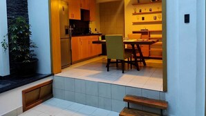 Une cuisine compacte avec des meubles en bois, un coin repas comprenant une table et des chaises, et un petit banc.