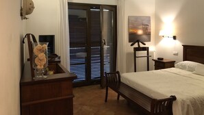 Une chambre à coucher avec un lit, un bureau avec une lampe, une chaise, un radiateur et un tableau accroché au mur.