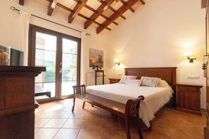 Ein Schlafzimmer mit einem hölzernen Bett, einer Bank, einem Nachttisch und Blick durch eine Glastür.
