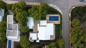 Vista aérea de una propiedad residencial con piscina, varias terrazas y abundante vegetación.