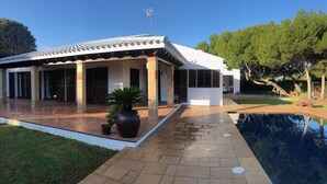 Una casa moderna con techo de tejas, un porche cubierto y una piscina.