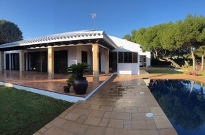 Una casa moderna con techo de tejas, un porche cubierto y una piscina.