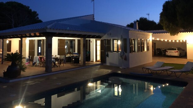 Une maison moderne avec une piscine, un patio couvert et une voiture garée dans le garage.
