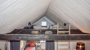 A loft bedroom with a sloped ceiling, two bunk beds, a window, and a radiator. - Pet friendly home in Beddingestrand (Beddingestrand)
