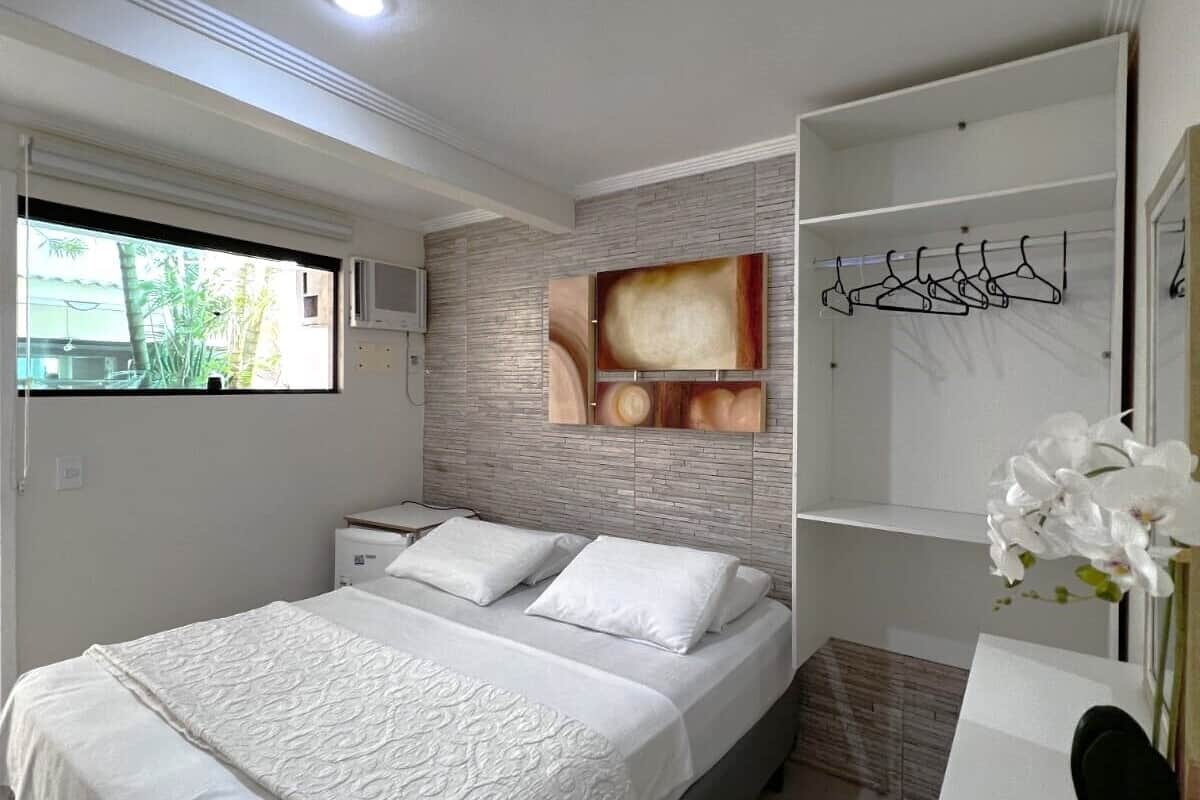A modern bedroom with a bed, a nightstand, a built-in wardrobe, and a window with a view of greenery.