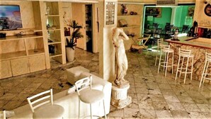 A hotel lobby with marble flooring, white furniture, a statue, and a bar area. - POUSADA OCEANIC (Arraial do Cabo)