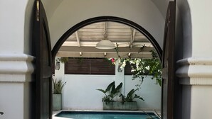 An arched doorway leading to a swimming pool area with a tiled floor, a manhole cover, and potted plants. - Beachfront 2 bedroom apartment with private pool -NEW LISTING (Fitts Village)