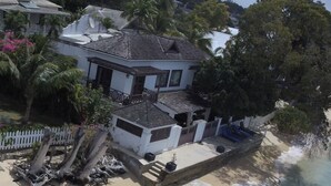 A beachfront property with a house, a small boat, and a sandy beach. - Beachfront 2 bedroom apartment with private pool -NEW LISTING (Fitts Village)