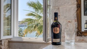 Une bouteille de Glenmorangie posée sur une surface en marbre, près d’une fenêtre offrant une vue sur des palmiers et une étendue d’eau.