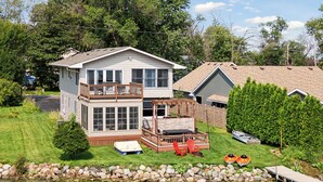 Ein zweistöckiges Haus mit Terrasse und Steg an einem See.