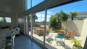 A spacious living area with a sliding glass door leading to an outdoor patio. - Maison Bord de mer Golfe du Morbihan (Vannes)