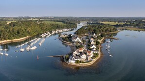 An aerial view of a coastal village with a marina filled with boats, surrounded by lush greenery and residential buildings. - Maison Bord de mer Golfe du Morbihan (Vannes)