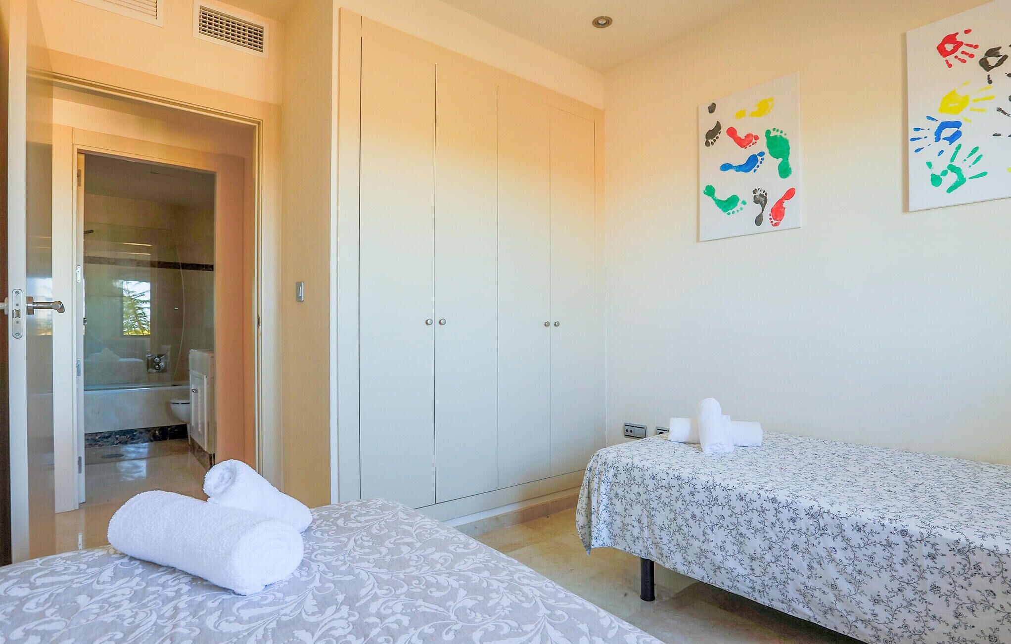 A hotel room with two beds, a bathroom, and a wardrobe.