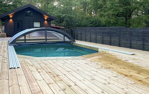 Relax by the pool surrounded by a deck and a small building with windows.