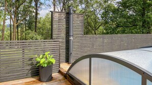 A wooden deck with a metal gate, a potted plant, and a glass-enclosed pool. - Gorgeous home in Skjold (Skjold)