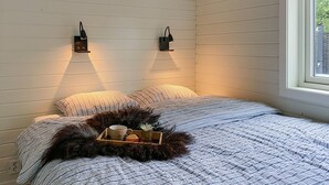 A bedroom with a bed, two wall-mounted lamps, a window, and a tray with a cup and a bowl on the bed. - Gorgeous home in Skjold (Skjold)