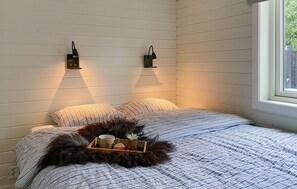 Relax in this serene bedroom with a large bed, wall-mounted reading lamps, and a decorative tray.