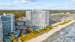 Un hôtel de grande hauteur doté de nombreux balcons, d’un espace piscine et offrant une vue sur la plage.