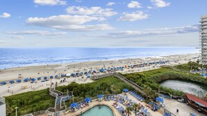 Un complexe hôtelier de bord de mer doté d’une piscine, de chaises longues et offrant une vue sur l’océan.