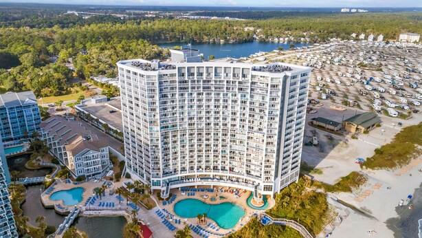 Un hôtel de grande hauteur doté de nombreux balcons, d’une piscine centrale et d’un port de plaisance avec des bateaux.