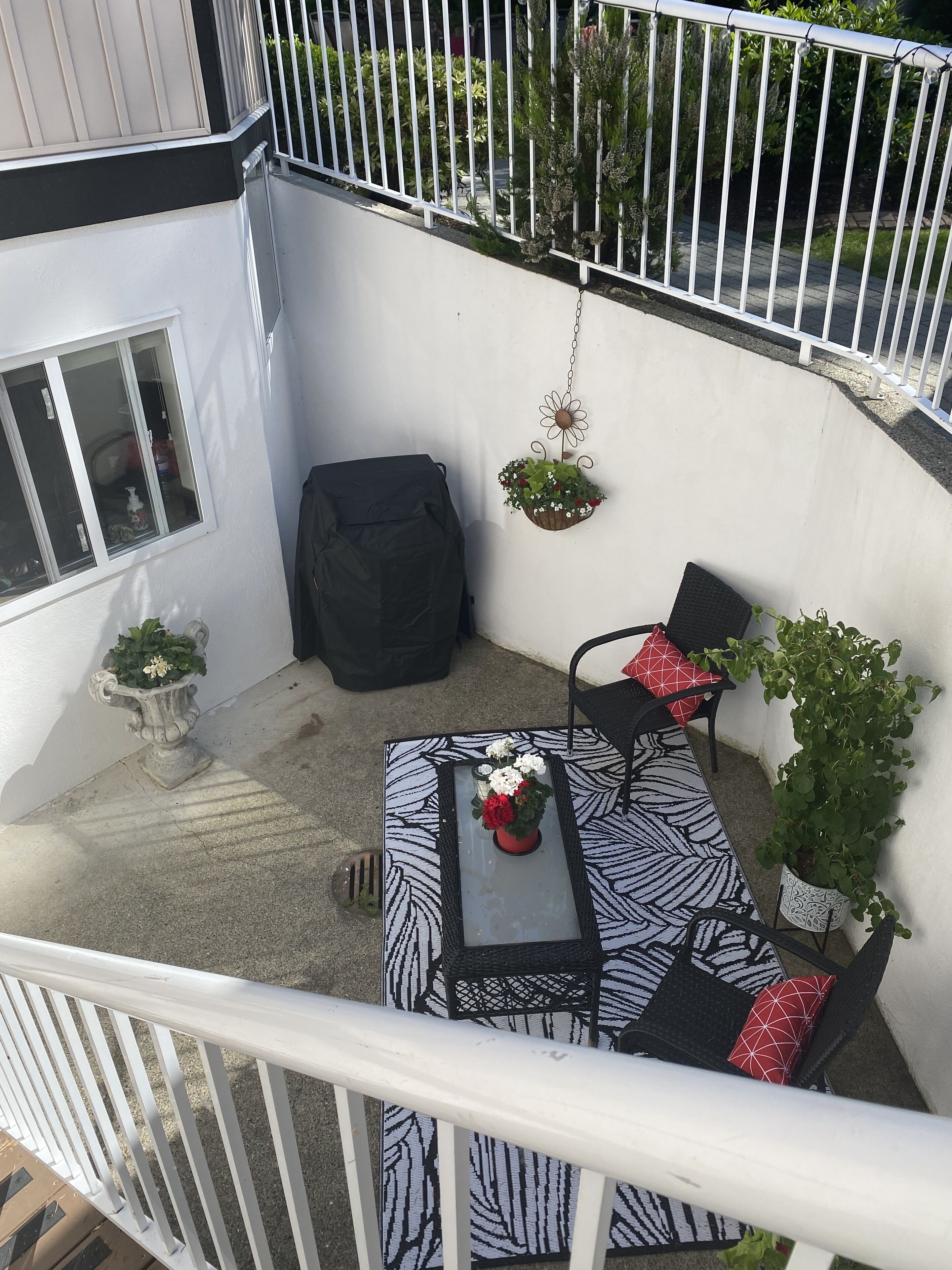 Ein Balkon mit Tisch, Stühlen, einem hängenden Blumentopf und einer Topfpflanze.