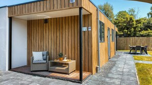 A modern wooden cabin with a number 192 sign, a small seating area with cushions, a potted plant, and a patio with a table and chairs. - Nice home in Heinkenszand with WiFi (Heinkenszand)