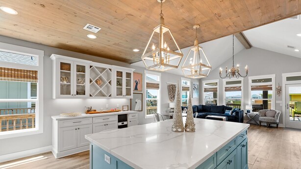 A spacious kitchen with a large island, white cabinetry, and a blue accent wall. - Steps from Beach: Sleeps 15, Hot Tub, Pet-Friendly (Crystal Beach)