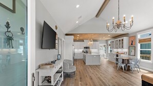 A spacious kitchen with white cabinets, a central island, and a dining area with a table and chairs. - Steps from Beach: Sleeps 15, Hot Tub, Pet-Friendly (Crystal Beach)