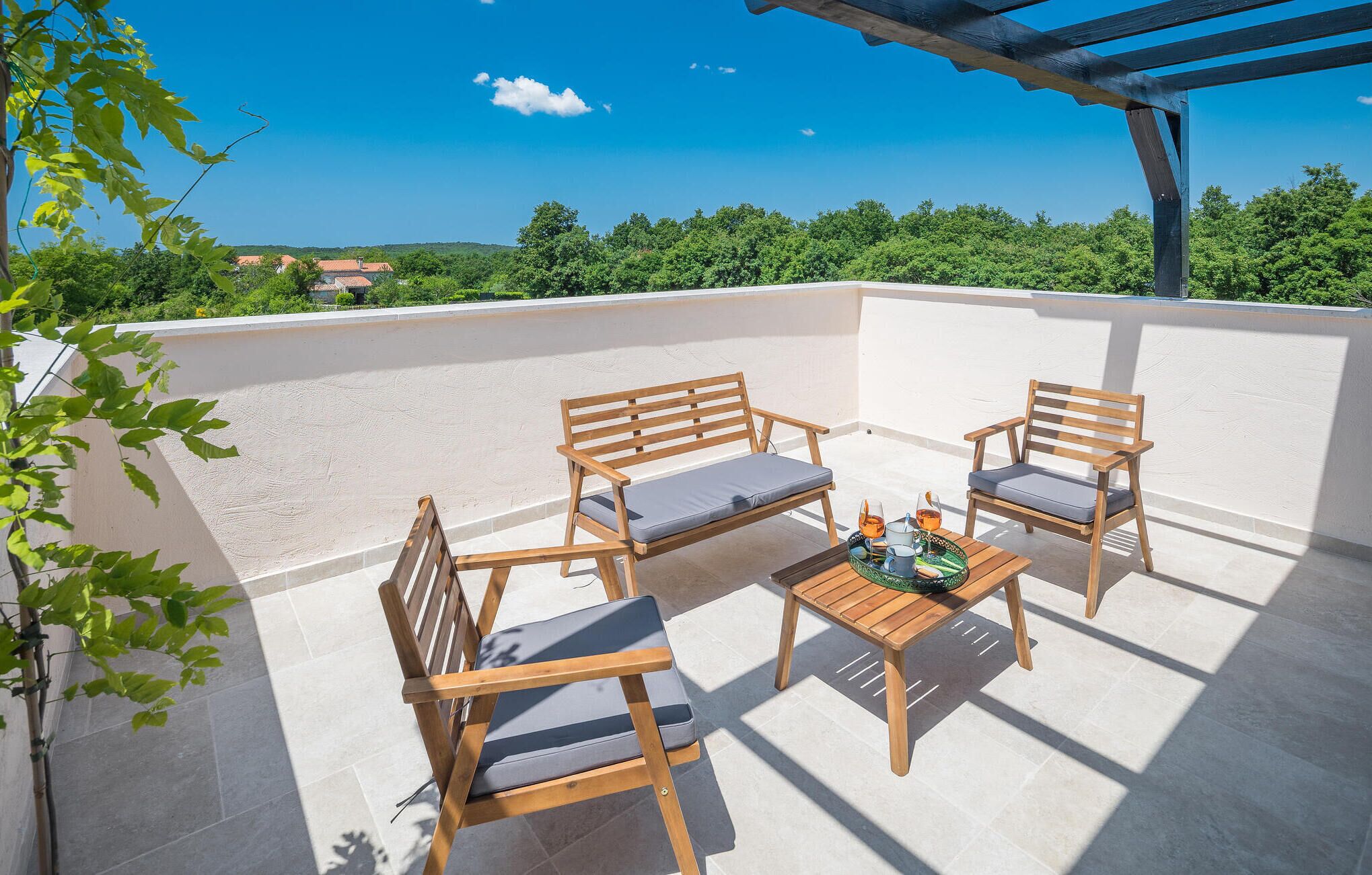 Une terrasse sur le toit avec deux chaises en bois et une table, une petite assiette décorative et un verre contenant une boisson.