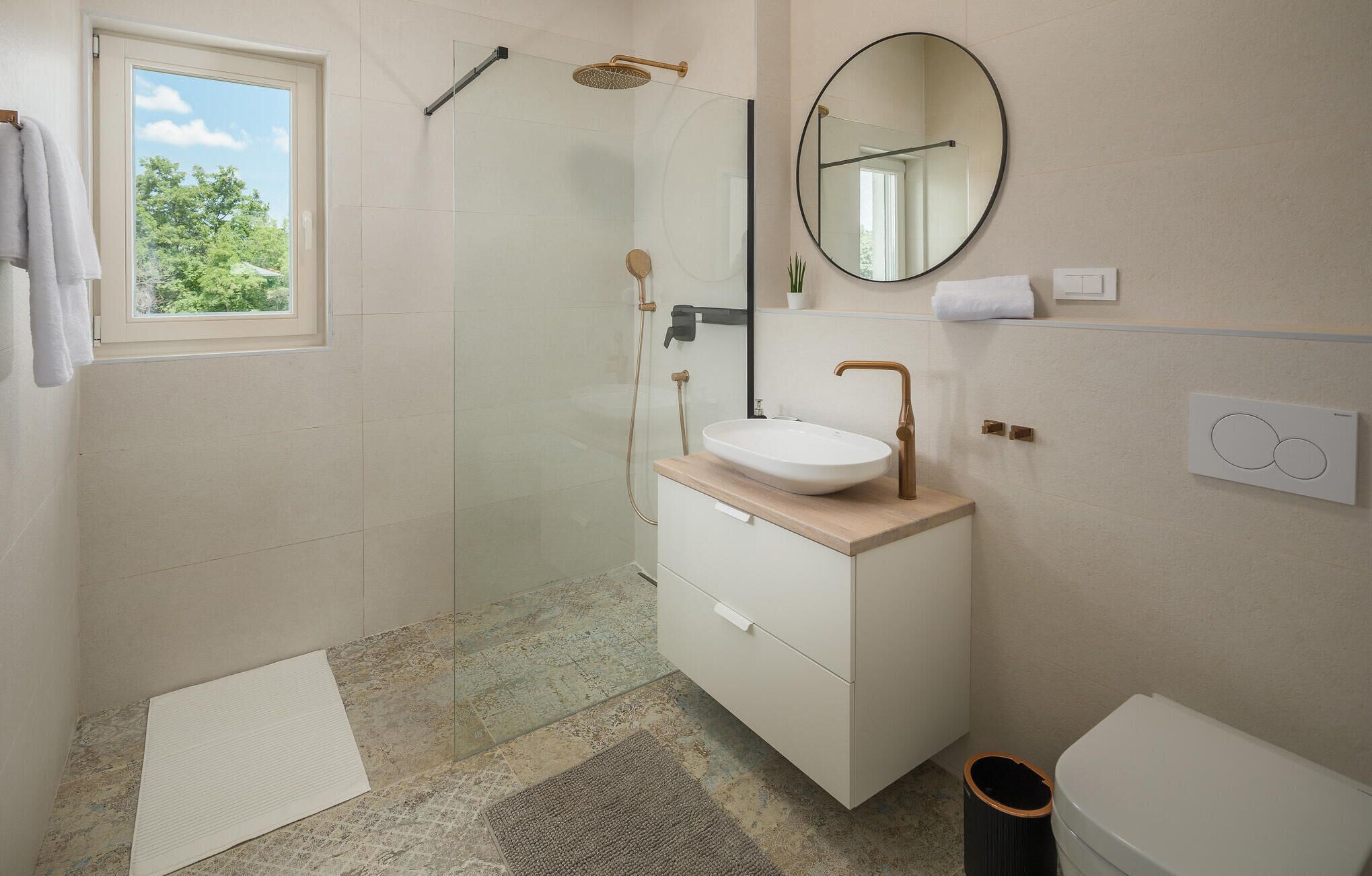 Un baño moderno con ducha de vidrio, un lavabo blanco y un espejo grande.