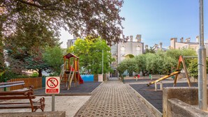 A playground with a wooden slide, a climbing structure, and a no dogs sign.