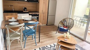 Eine moderne Küche mit schwarzen Schränken, einer Mikrowelle, einem Herd und einem Kühlschrank. Es gibt einen Esstisch mit Stühlen und einen kleinen runden Tisch mit Kerzen.