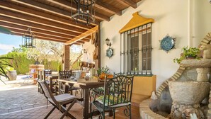 An outdoor patio with a wooden table and chairs, a stone fountain, and decorative wall plates. - 4 bedroom awesome home in Arriate (Arriate)