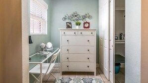 A small, well-lit room with a desk, a dresser, and a wall-mounted bicycle decoration. - Spanish Colonial Revival Studio Unit 3 (Phoenix)