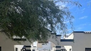 A pathway leading to a row of white buildings with a central archway. - Spanish Colonial Revival Studio Unit 3 (Phoenix)