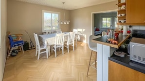 A compact kitchen with a dining area, wooden flooring, and a view through an open door. - 2 bedroom cozy home in Traryd (Traryd)