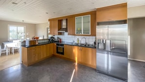 A modern kitchen with stainless steel appliances, wooden cabinets, and a large island. - 2 bedroom cozy home in Traryd (Traryd)
